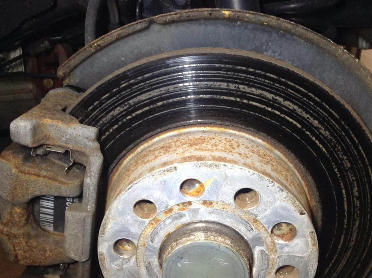 Damaged brake rotor with deep circular scoring, grooves, and surface corrosion